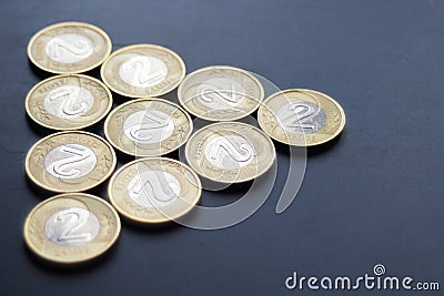 A triangle of Polish two zloty coins on worn dark matte background. Stock Photo