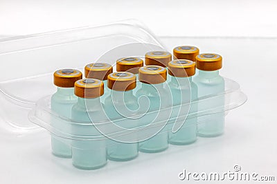 Ten vaccine bottles inside opened translucent plastic box Stock Photo