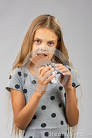 A ten-year-old girl eats a chocolate bar Stock Photo