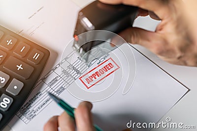 Tender acceptance - hand put a approved stamp on financial bill Stock Photo