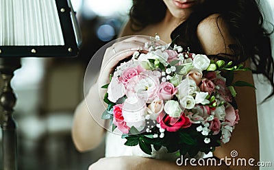 Tender bride touches a pink wedding bouquet standing in the hotel Stock Photo