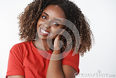 Tender friendly-looking attractive young african-american woman with curly afro hairstyle combing hair with hand gently Stock Photo