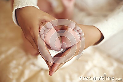 Tender interior photo of cute baby feet in mom hands Stock Photo