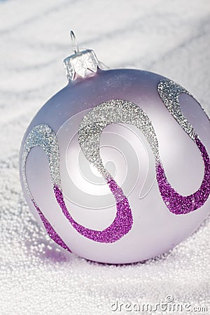 Tender lilac Christmas bauble on to snow. Stock Photo