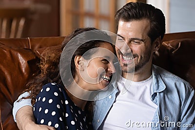 Tender millennial husband smiling clasping to chest beloved laughing wife Stock Photo