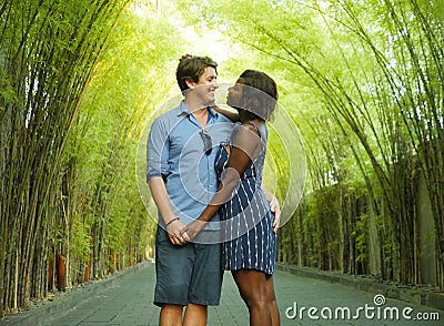 Tender mixed ethnicity couple cuddling outdoors with attractive black afro American woman and handsome Caucasian boyfriend or Stock Photo