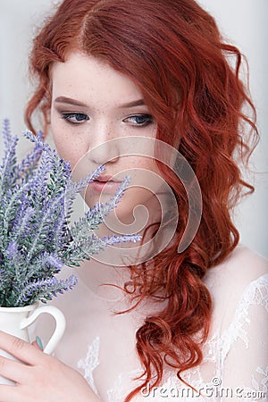 Tender retro portrait of a young beautiful dreamy redhead woman in beautiful white dress with bouquet of lavender. Stock Photo