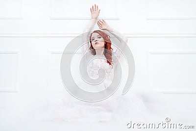Tender retro portrait of a young beautiful dreamy redhead woman in beautiful white dress. Stock Photo