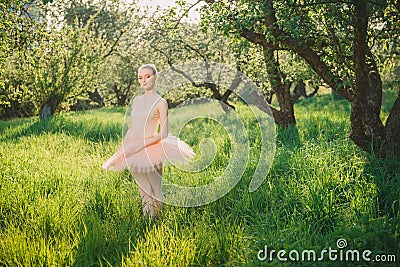 Tender and romantic dancer woman in green landscape at sunset Stock Photo