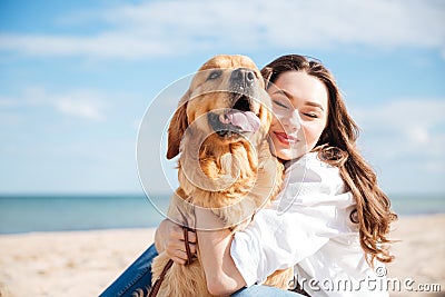 Tender smiling young woman hugging her dog on the beach Stock Photo
