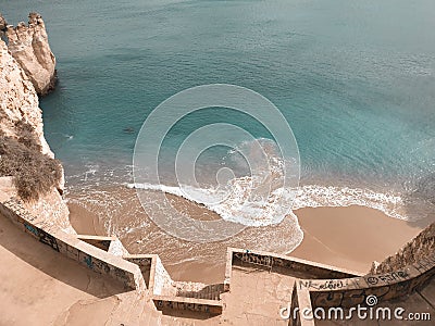 A sharp stairs lead to the the warm cerulean sea and the mild sand among the ridiculously shaped rocks Stock Photo