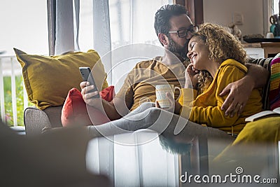 Tenderness time moment for mature caucasian couple at home sitting on the couch together - love and relationship adult people Stock Photo