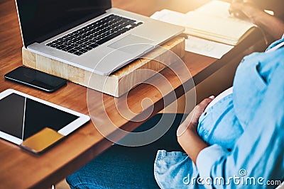 Tending to business before baby arrives. a pregnant woman using a laptop while working from home. Stock Photo