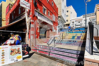 Colourful commercial empty street with restaurants shopping stores, ornate painted stair and Editorial Stock Photo