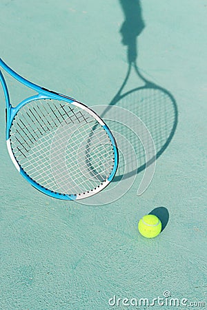 Tennis ball and racket on blue hard tennis court. Shadow of a hand holding tennis racket on the tennis court. Side view, copy Stock Photo