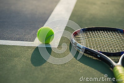 Tennis ball and racket under late evening sunlight Stock Photo