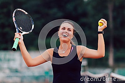 Happy girl raised her racket and ball after winning in tennis tournament Stock Photo