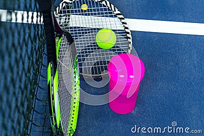 Tennis rackets, a bottle of water and a ball against the background of a stretched tennis net on an indoor tennis court Editorial Stock Photo