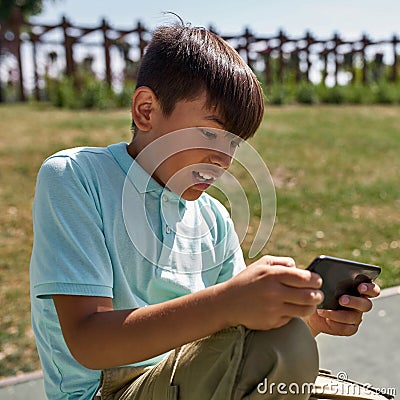 Tense boy play video game on smartphone outdoors Stock Photo