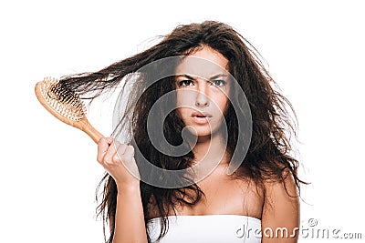 Brunette woman holding wavy unruly hair in comb isolated on white Stock Photo