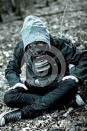 Tense child in gas mask sitting on ground Stock Photo