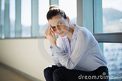 Tense female business executive sitting with hand on forehead Stock Photo