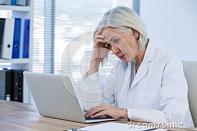 Tense female doctor working on her laptop Stock Photo