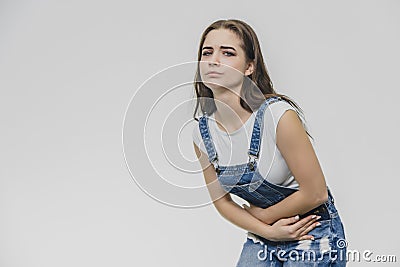 A tense young beautiful woman holds her arms on her stomach, feels painful emotions. She suffers from pain after hard Stock Photo