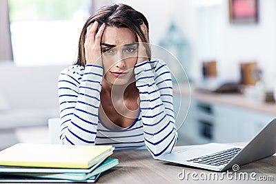 Tensed woman with head in hands sitting with laptop Stock Photo