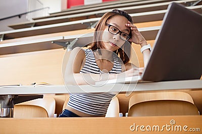Tensed woman using laptop in classroom Stock Photo