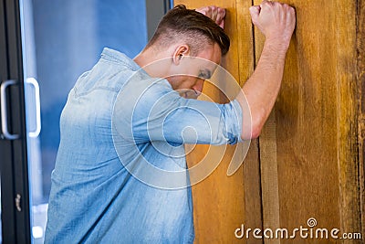 Tensed young man leaning on door Stock Photo