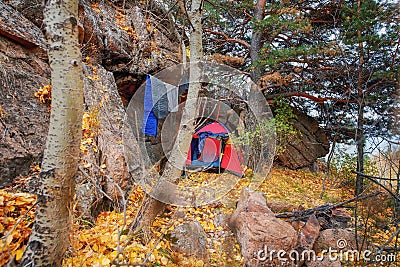 Tent on the top of the mountain hidden behind stones and fixed to the trees, sleeping bags Stock Photo