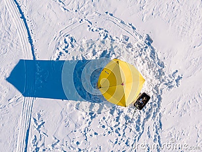 Tent for winter ice fishing, top aerial view, fisherman holding rod in hole lake Stock Photo