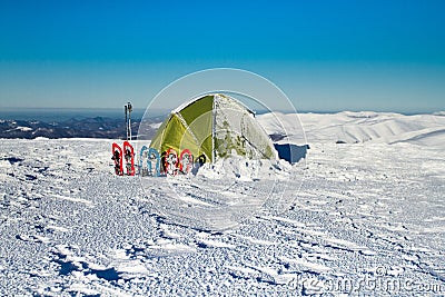 Tent winter mountains.Tent stands in the mountains in the snow. Snowshoes are beside the tent. Stock Photo