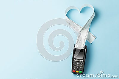 Terminal cash register machine POS for payments and long roll paper cash tape in heart shaped on blue background. Copy space for Stock Photo