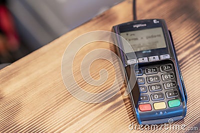 Terminal for cashless payment on a wooden background in a cafe Editorial Stock Photo