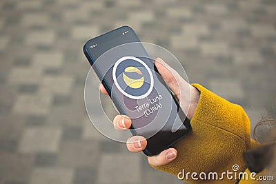 Terra Luna cryptocurrency symbol, logo. Business and financial concept. Hand with smartphone, screen with crypto icon Editorial Stock Photo