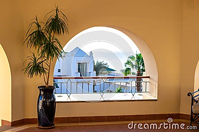 Terrace with arch overlooking the sea. Tall plant in a pot on a spacious balcony. A semicircular window overlooking the villa and Stock Photo