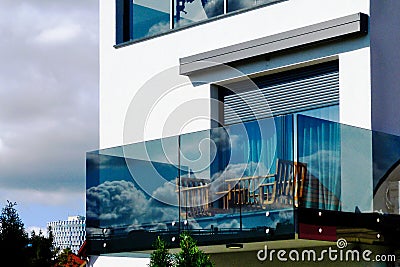 terrace balcony with glass balustrade railing. wood patio furniture. white stucco exterior. Stock Photo