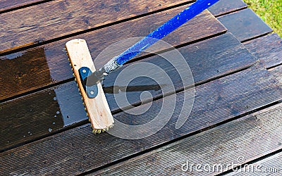 Terrace cleaning. Renovating a gray terrace using a hard scrub brush and green gel for renovating faded, gray boards Stock Photo