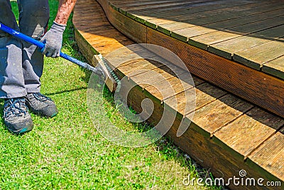 Terrace cleaning. Renovating a gray terrace using a hard scrub brush and green gel for renovating faded, gray boards - an Stock Photo