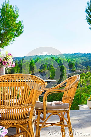 Terrace of luxurious white villa with wicker chairs table flowers bouquet on table fascinating view of valley mountains Stock Photo