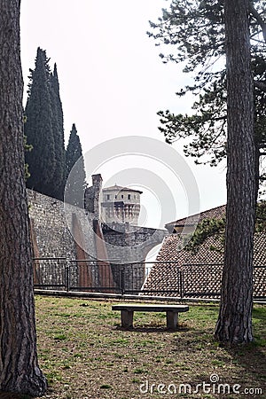 Terrace with trees and benches next to a boundary wall of a castle with a bridge in the distance Stock Photo