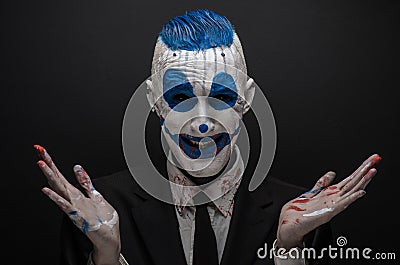 Terrible clown and Halloween theme: Crazy blue clown in black suit isolated on a dark background in the studio Stock Photo