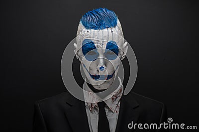 Terrible clown and Halloween theme: Crazy blue clown in black suit isolated on a dark background in the studio Stock Photo