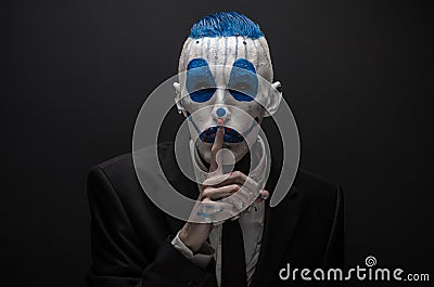 Terrible clown and Halloween theme: Crazy blue clown in black suit isolated on a dark background in the studio Stock Photo