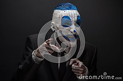 Terrible clown and Halloween theme: Crazy blue clown in black suit isolated on a dark background in the studio Stock Photo