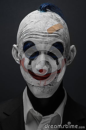 Terrible clown and Halloween theme: Crazy terrible blue clown in black suit isolated on a dark background in the studio Stock Photo