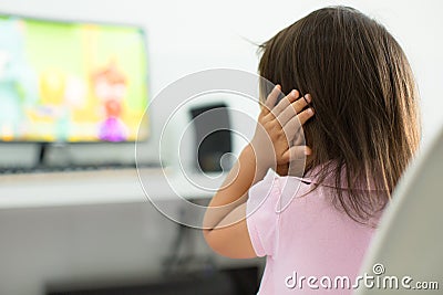 A terrified child, afraid of the loud sounds from the television. Autism Stock Photo