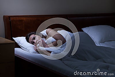Terrified woman lying in bed Stock Photo